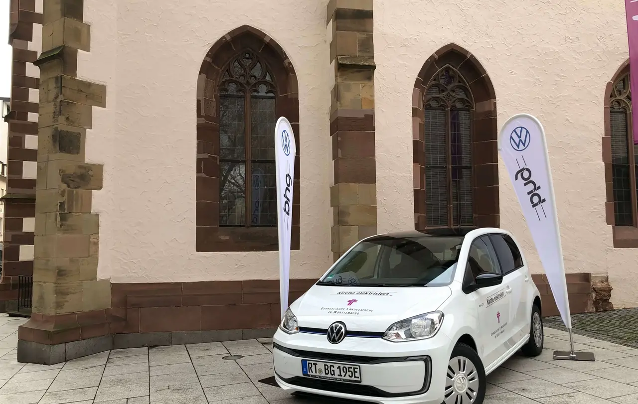 Ein E-Up mit dem Schriftzug „Kirche elektrisiert“ und dem Logo der Evangelischen Landeskirche in Württemberg ist vor der Tagungsstätte Hospitalhof platziert.