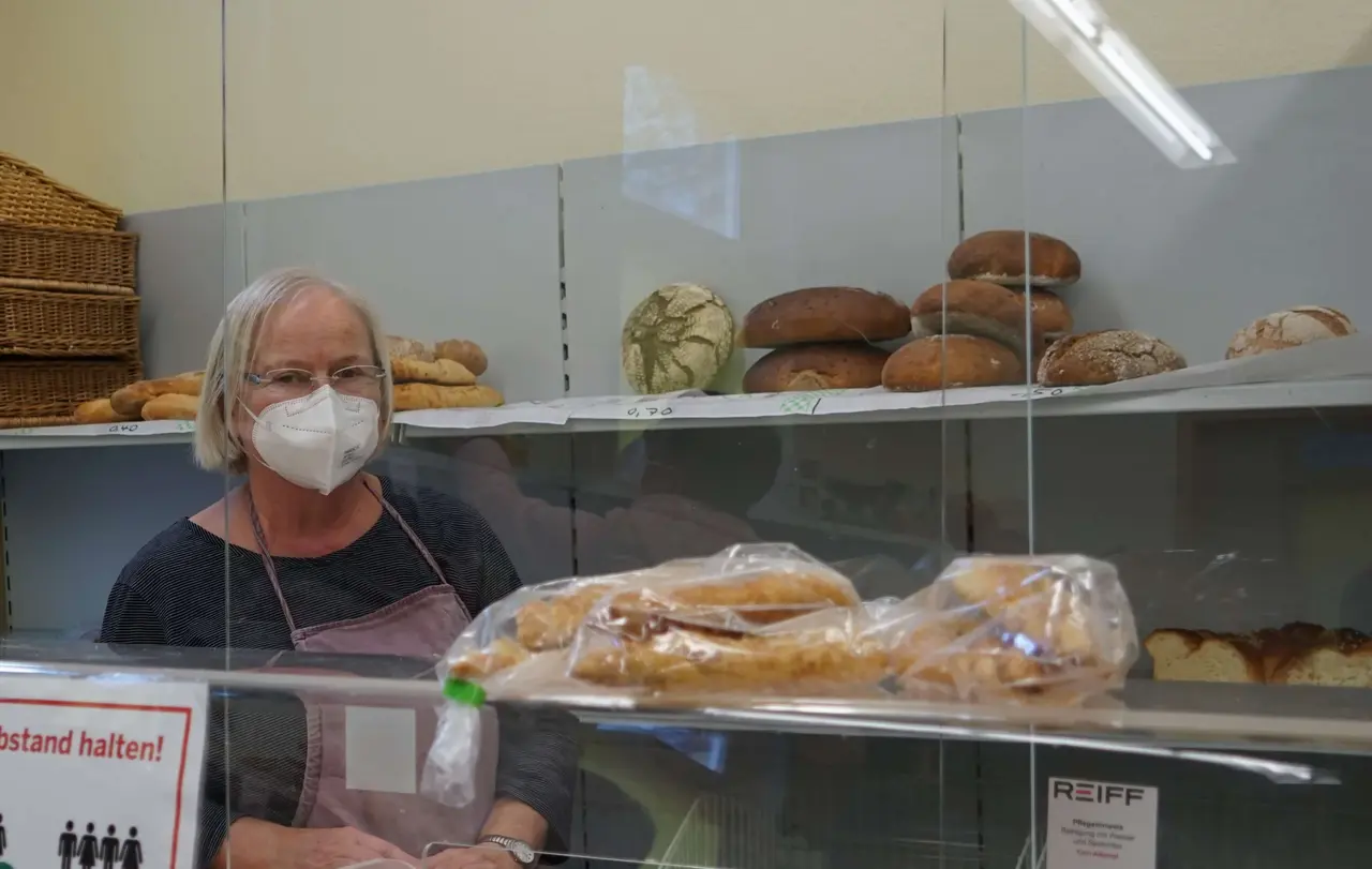 Hinter einer Theke steht die Ehrenamtliche Anna Hatwig und versorgt die Menschen mit Brot. Die Tafel erhält weniger Brotspenden als früher.
