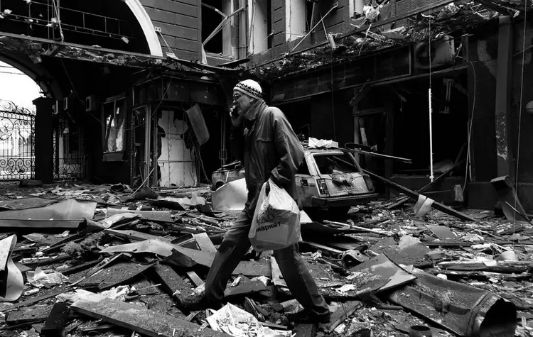 Ein Mann steht in Charkiw im Hof eines Hauses, das zum Großteil in Trümmern liegt.