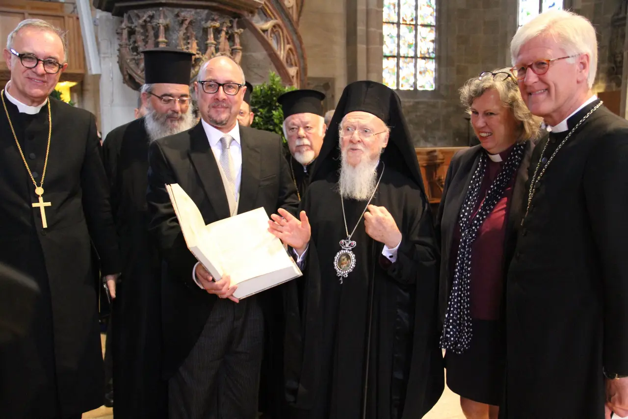 Patriarch Bartholomaios überreicht Professor Dr. Michael Tilly eine Faksimile-Ausgabe des griechischen Alten Testaments; mit Landesbischof Dr. h. c. Frank Otfried July (links) und dem EKD-Ratsvorsitzenden Heinrich Bedford-Strohm (rechts).