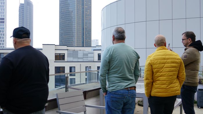 Vier Männer bei einer Drehpause auf einem Dach in Frankfurt