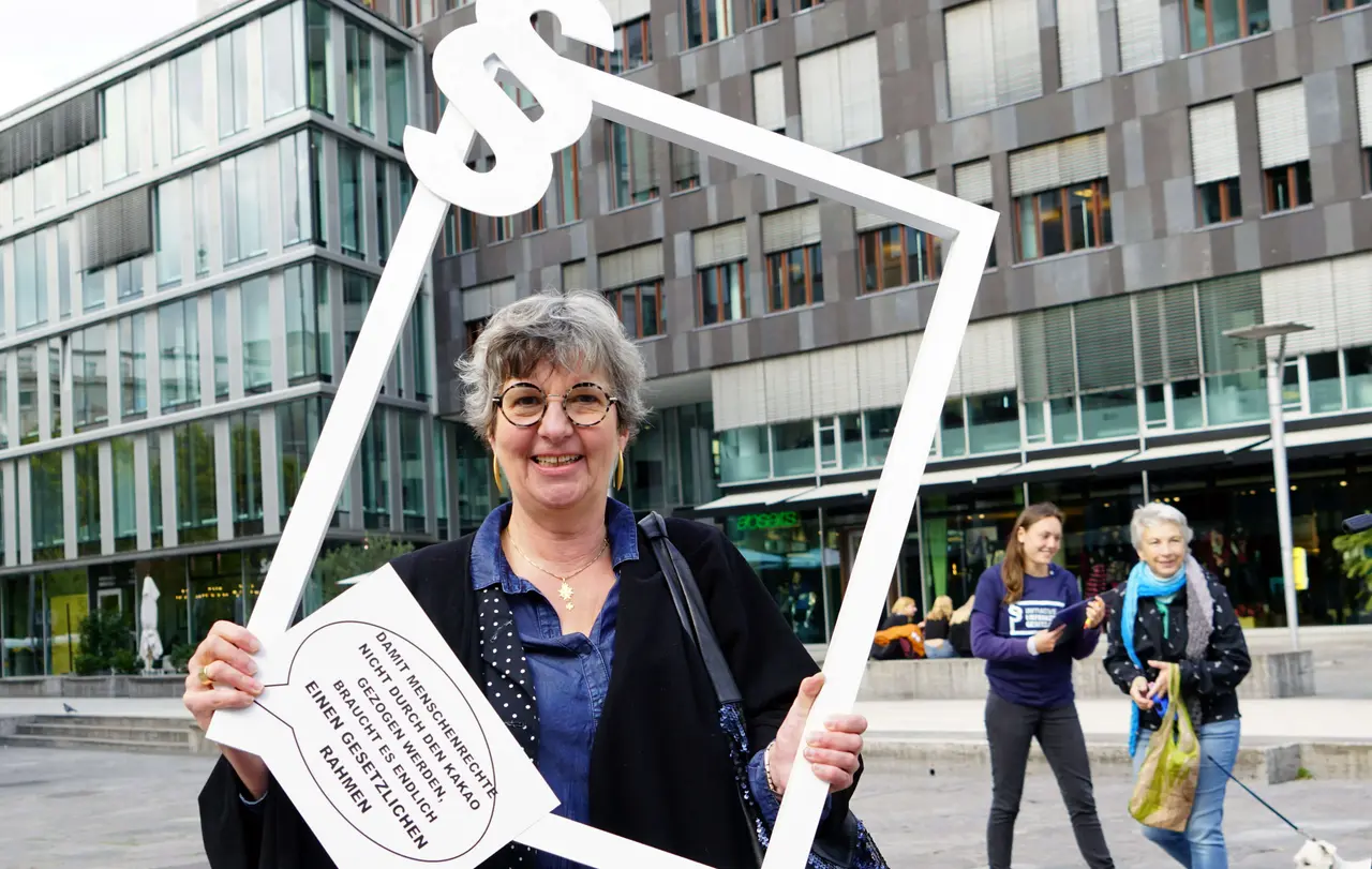 Die Stuttgarter Prälatin Gabriele Arnold mit dem symbolischen Gesetzesrahmen, den die Unterstützer der Aktion „Lieferkettengesetz“ einfordern. Im Hintergrund bittet eine Aktivistin Passanten auf dem Kleinen Schlossplatz um Unterstützer-Unterschriften.