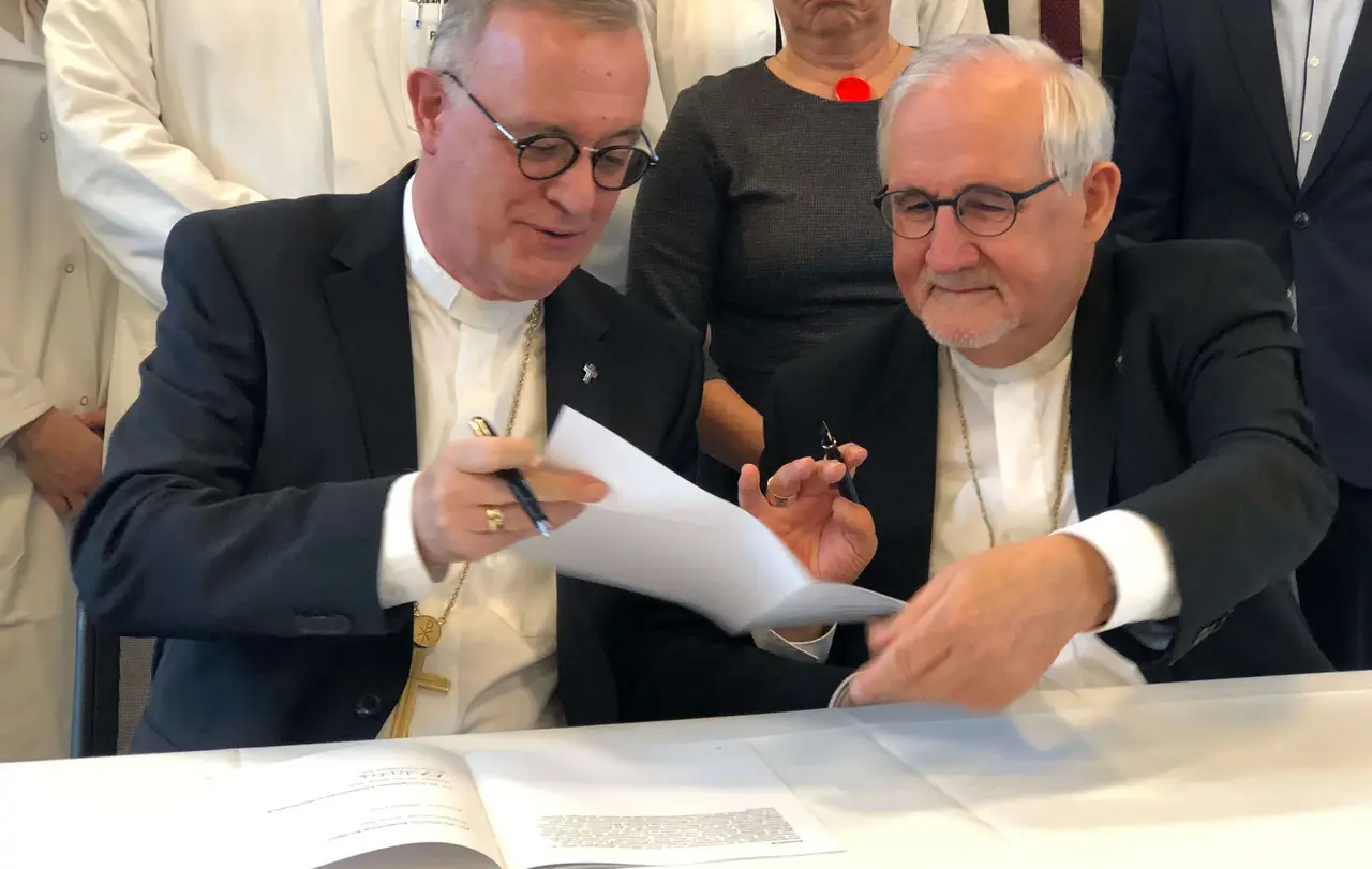 Landesbischof Dr. h. c. Frank Otfried July (l.) reicht die Rahmenvereinbarung zur Unterschrift an Bischof Dr. Gebhard Fürst weiter.