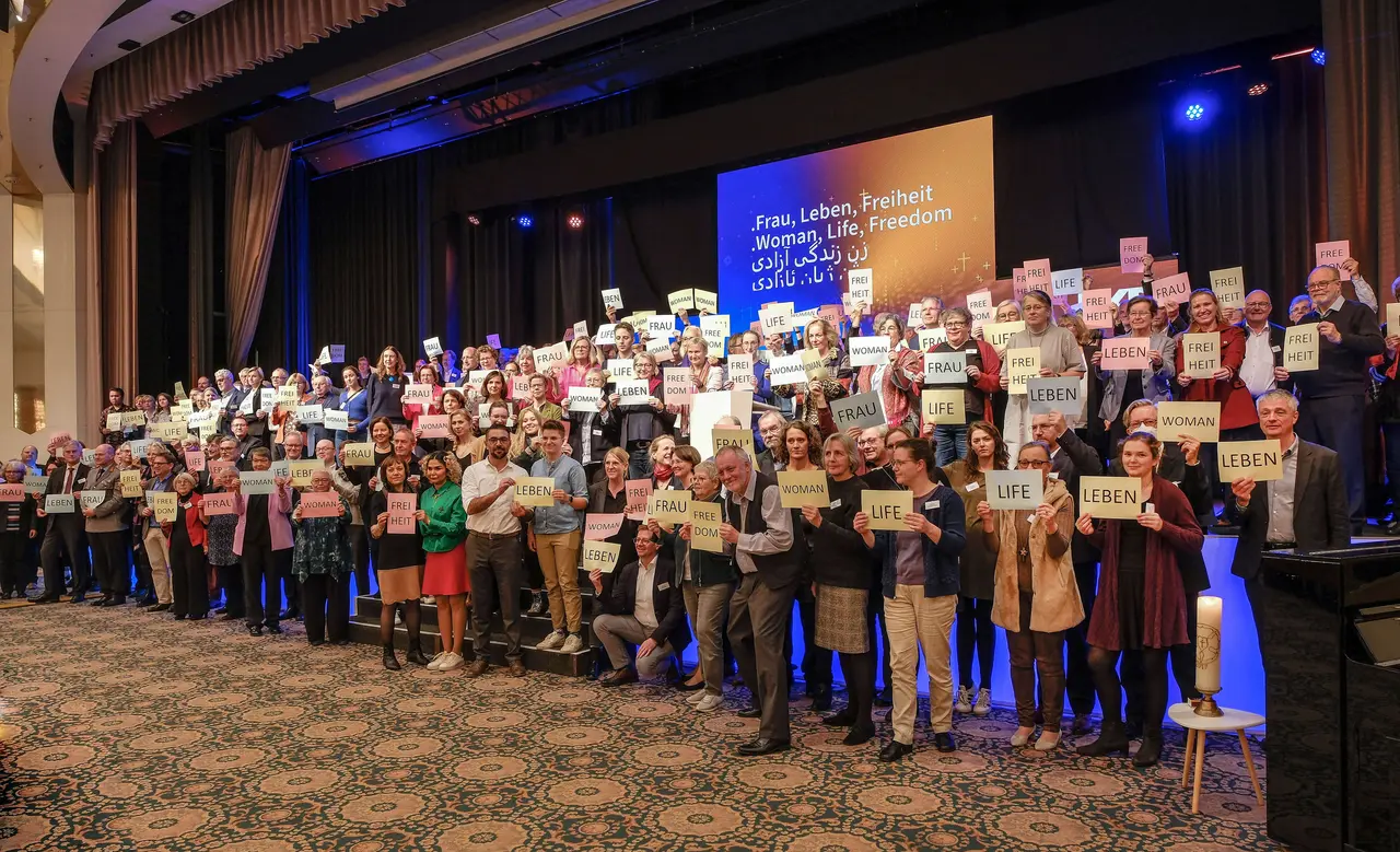 EKD-Synodale setzen bei ihrer Tagung ein Zeichen der Solidarität mit den Protesten im Iran. Auch Landesbischof Ernst-Wilhelm Gohl hat daran teilgenommen, auf dem Bild ist er allerdings hinter einer anderen Person fast ganz versteckt.
