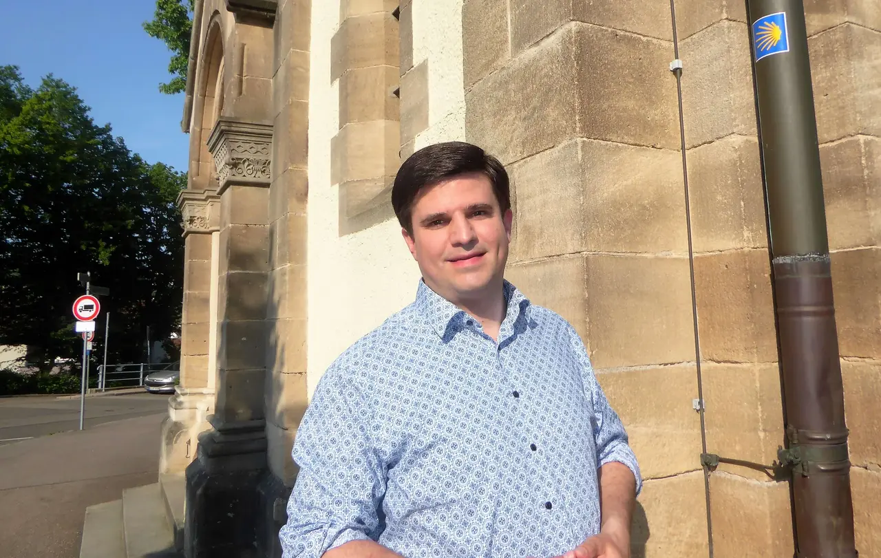 Pfarrer Enno Knospe vor dem kleinen Muschel-Zeichen des Jakobswegs an der St. Bernhardt-Kirche in Esslingen.