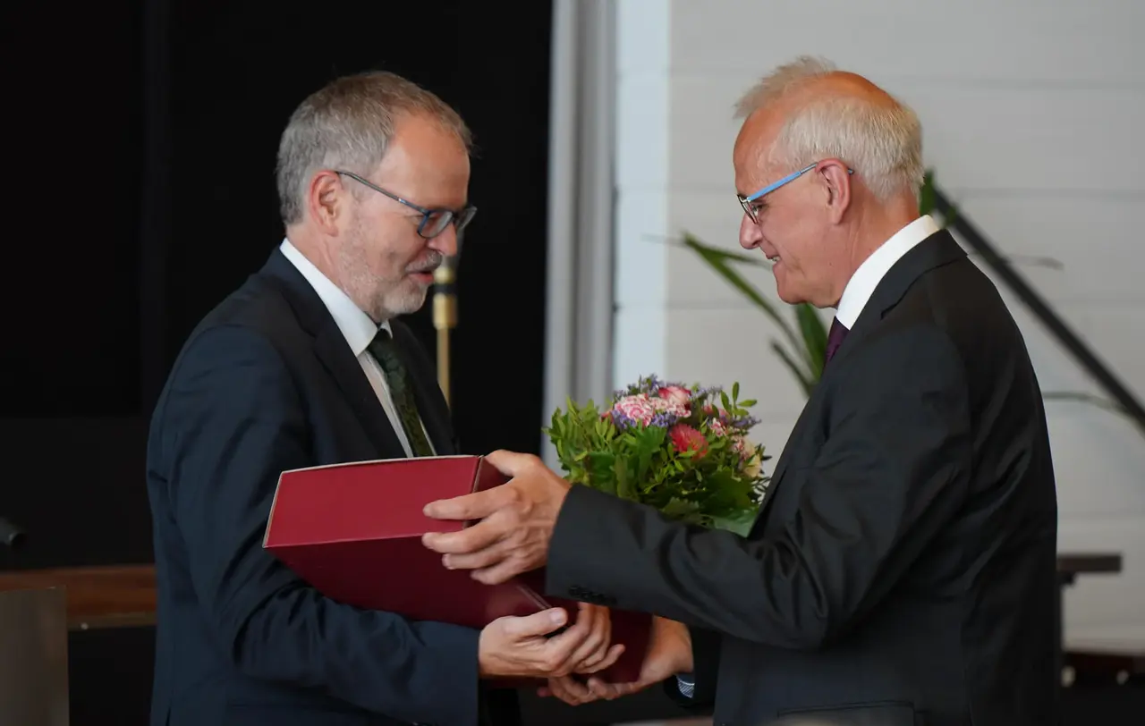 Stefan Werner, Direktor im Oberkirchenrat (links), überreicht Hans-Peter Duncker ein Geschenk zum Eintritt in den Ruhestand.