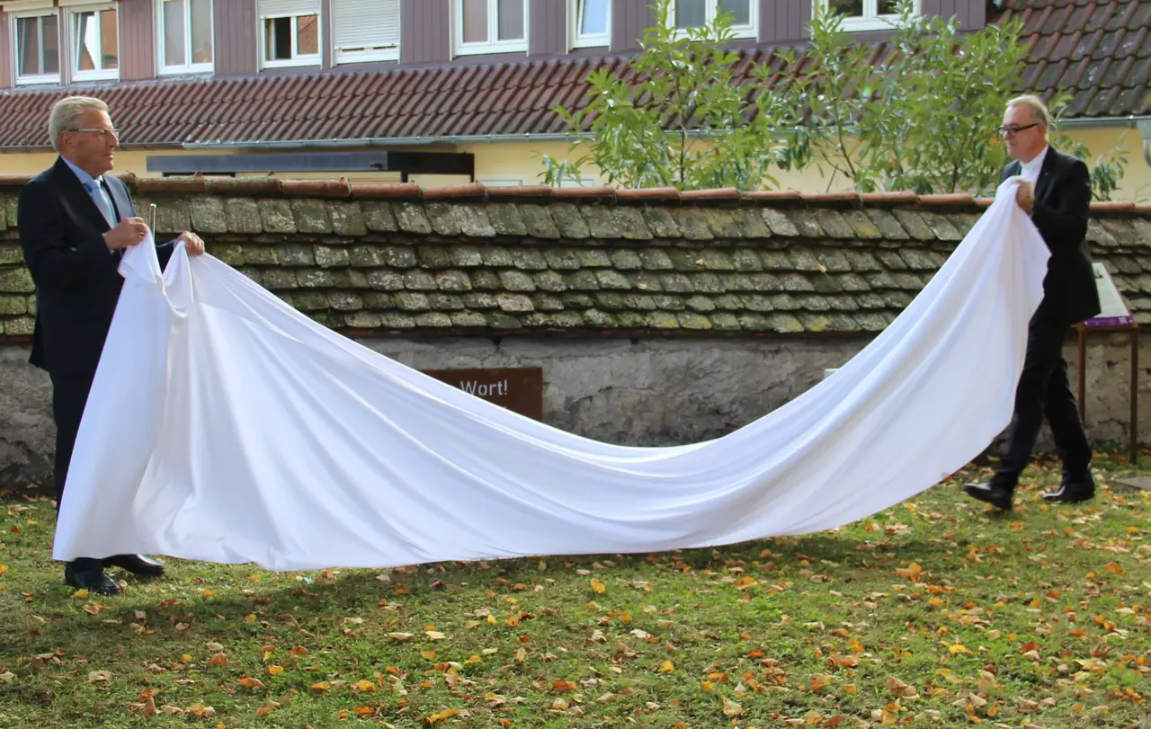 Richard von Jan (l.) und Landesbischof Dr. h.c. Frank Otfried July enthüllen die Gedenktafel im Kirchgarten.