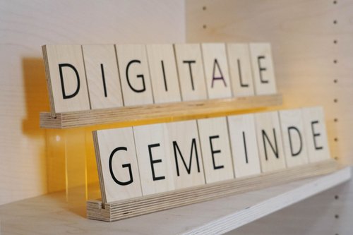 Das Bild zeigt Holzbuchstaben, die den Text "Digitale Gemeinde" formen.