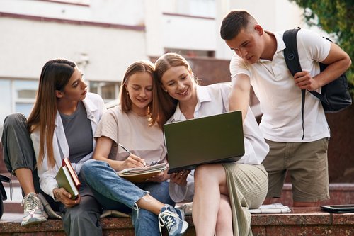 Gruppe von vier Studierenden, die in einen Laptop schauen