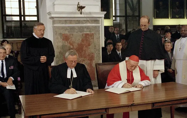Erstunterzeichnung der Gemeinsamen Erklärung am 31. Oktober 1999 in Augsburg: Der damalige Braunschweiger Landesbischof Christian Krause unterschrieb im Namen des Deutschen Nationalkomitees des Lutherischen Weltbundes, für die römisch-katholische Kirche unterzeichnete Kurienkardinal Edward Idris Cassidy.