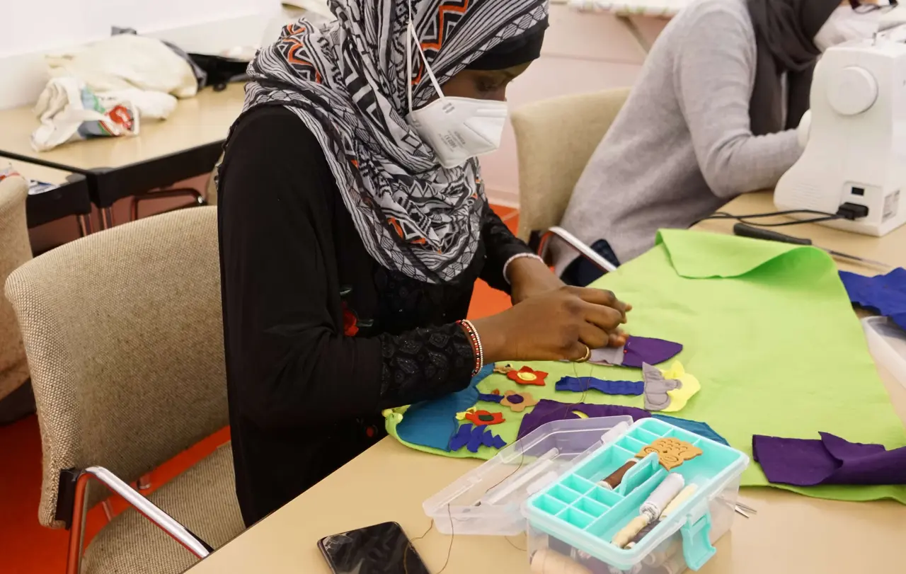 Binta näht Blumen auf eine grüne Filzdecke.